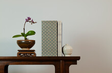 Purple Orchid, Chinese Antique Ceramic And Traditional Style Book On Wooden Table Against White Wall