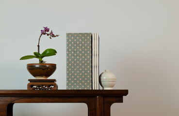 Purple orchid, Chinese antique ceramic and traditional style book on wooden table against white wall