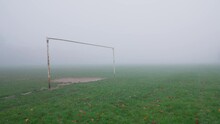 A rusty goalpost on a foggy football field during autumn. Slow motion, static shot.