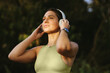 © Jacob Lund - Fit woman listening to warmup music on headphones outdoors