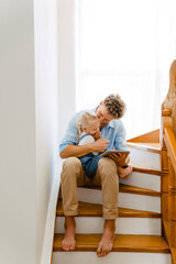 Young father and his daughter using tablet computer on stairs at home