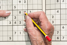 Old Woman's Hand With Pencil Doing A Sudoku. 