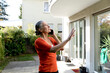 © Westend61 - Senior woman talking on mobile phone in front of house