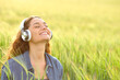 © Antonioguillem - Happy woman listening audio in a field and breathing
