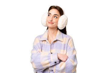 Wall Mural - Young caucasian woman wearing winter muffs over isolated chroma key background making doubts gesture while lifting the shoulders