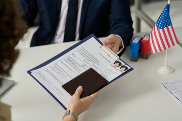 Wall Mural - Close up of woman handing visa application form to worker in US Immigration office