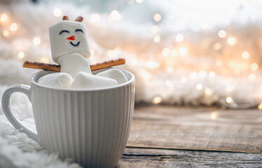 Wall Mural - Close up, mug of hot drink with marshmallow snowman on blurred background.