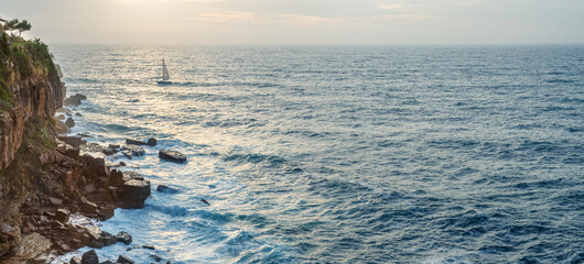 Wall Mural - cloudy sky and foaming waves approaching rocky shore of the atlantic ocean. beautiful nature backgro