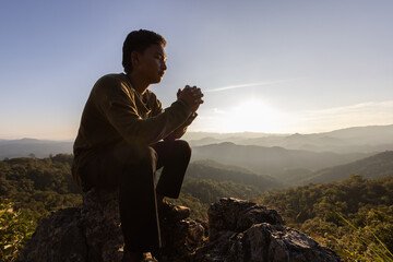 Wall Mural - Silhouette. Man praying to god on the mountain. Pray with hands with faith in religion and belief in God on blessing basis. the power of hope or love and devotion.