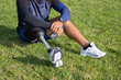 © KAMPUS - Close-up of Caucasian man with mechanical leg sitting on grass. Sportsman in blue shorts and white sneakers photographed in park. Sport, disability concept