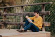 © ADDICTIVE STOCK - Young man sitting on wooden bridge reading book