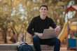 © ADDICTIVE STOCK - Happy man working on laptop in park