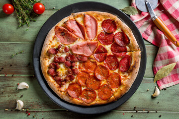 Wall Mural - Pizza with Bavarian sausages on green wooden table top view