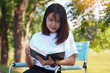 © Aoy_Charin - Asian woman reading a book on a lawn chair in the park Female concept doing outdoor activities such as reading, working, listening to music, having a picnic, etc.soft and selective focus.