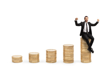 Businessman seated on top of a coin pile and gesturing happiness