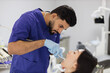 © sofiko14 - Happy patient and dentist concept. Young bearded asian male stomatologist treating teeth of a beautiful asian woman patient, using tooth drill. Oral health and hygiene.