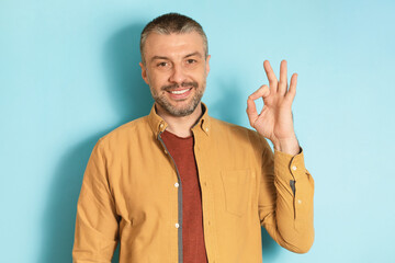 Poster - I'm fine. Portrait of happy mature man doing approval ok gesture and smiling at camera over blue studio background