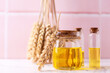 Bottles with organic wheat germ oil against pink tiled wall.  Natural skin care products. Beauty blogging, salon treatment concept. Selective focus. Place for text.