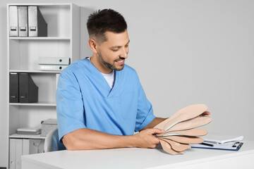 Sticker - Handsome male orthopedist showing insoles in hospital