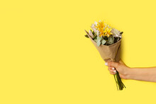 Mano De Mujer Sosteniendo Una Ramo De Flores Naturales Sobre Un Fondo Amarillo Liso Y Aislado. Vista De Frente Y De Cerca. Copy Space