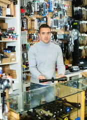 Sticker - Salesman standing at counter in arms shop and presenting rifle telescope.