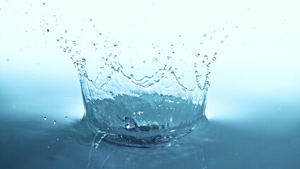 Wall Mural - Water splash crown isolated on soft blue background.