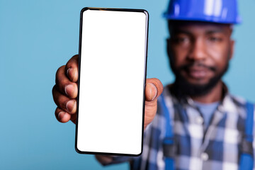 professional man holding smartphone with white screen display in studio, using work uniform and prot