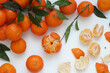 Tangerine and clementine citrus fruits with leaves on white background. Group of arranged mandarins and clementines with leaves, peeled fruit and scattered peel. Top view.