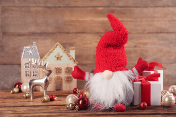 Wall Mural - Cute Christmas gnome, gift boxes and festive decor on table against wooden background