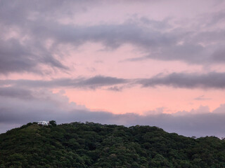 Poster - Pink  sunset over green hill with house