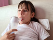 Sick child lies in bed and makes inhalations using nebulizer