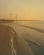 Offshore windmills with morning sky, windmill park in the ocean view of wind turbine beach. Green energy. 