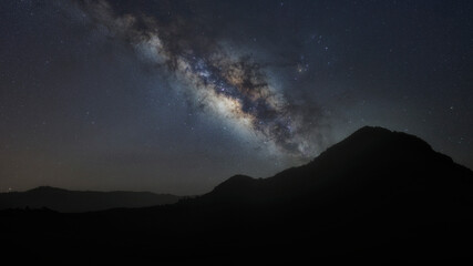 panorama mountain silhouette and blue night sky milky way and star on dark background. universe called,nebula and galaxy with noise and grain. Cassiopeia is a constellation in the northern sky. 