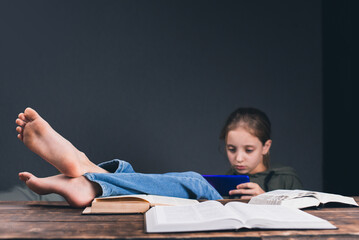 a girl with a phone in her hands. the girl plays on the phone, ignoring books and studies. open book