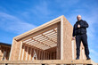 © anatoliy_gleb - Developer building wooden frame house in Scandinavian style barnhouse. Bald man standing on construction site, inspecting quality of work, showing thumbs up on sunny day with blue sky on background.