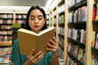 © AntonioDiaz - Attractive reader woman enjoying a new novel at the book shop