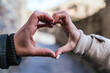 © Jorge - Close up shot of young couple joining hands to make the shape of a heart.