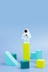 plastic figurine of an astronaut in a spacesuit and geometric shapes on blue background. children's 