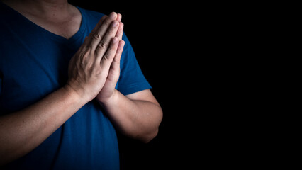 An adult whose hand is prayed on the dark background.Respect for belief in religion and God. front view. peace concept.