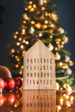 alfabet polski na drewnianej tablicy w kształcie domku, w świątecznej aranżacji, z choinką w tle, na boże narodzenie, christmas