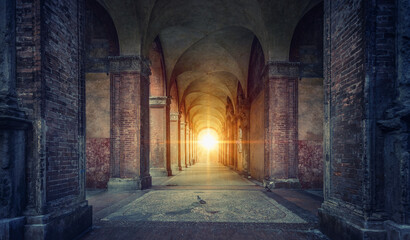 Canvas Print - Rays of divine light illuminate old arches and columns of ancient buildings. Bologna, Italy. Conceptual image on historical, religious and travel theme.