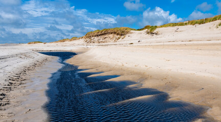 Fototapete - Panoramic view of “Hörnum odde“ a wild sandy beach on Sylt Island Germany. National Park “Wattenmeer“ is natural reserve and world heritage. Small tidal stream with dark water flowing towards the sea.