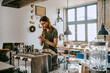 © Maskot - Young female entrepreneur preparing coffee while standing by counter in studio