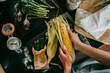 © Maskot - Directly above view of female chef peeling fresh corn at studio kitchen
