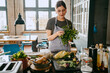 © Maskot - Female chef wearing apron doing quality check of cilantro standing in studio kitchen