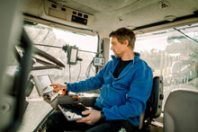 Farmer Operating Computer Sitting In Tractor At Farm