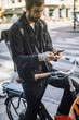© Maskot - Businessman using smart phone while sitting on cargo bike