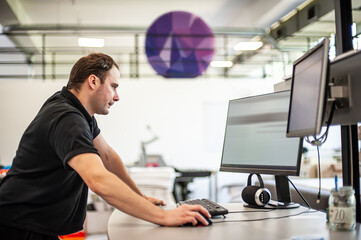 An experienced technician works on a printer computer in a printing shop. Production work. Check the print quality.