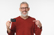 © InsideCreativeHouse - Smiling caucasian mature middle-aged bank employee man client customer pointing at credit card with cashback cashless transactions payment e-banking loan debt isolated in white background