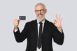© InsideCreativeHouse - Successful caucasian mature middle-aged businessman ceo boss bank employee worker holding credit card with copy space free space mockup showing okay gesture in white background
